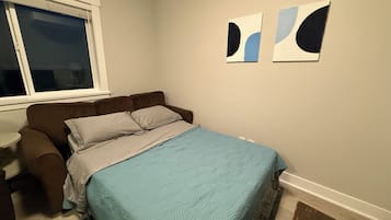 A bedroom with a bed, a window, and two wall art pieces.