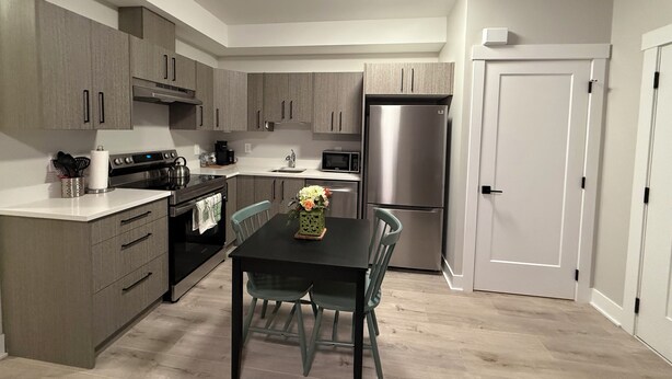 Una cocina compacta con electrodomésticos modernos, una mesa de comedor con sillas y una puerta blanca.