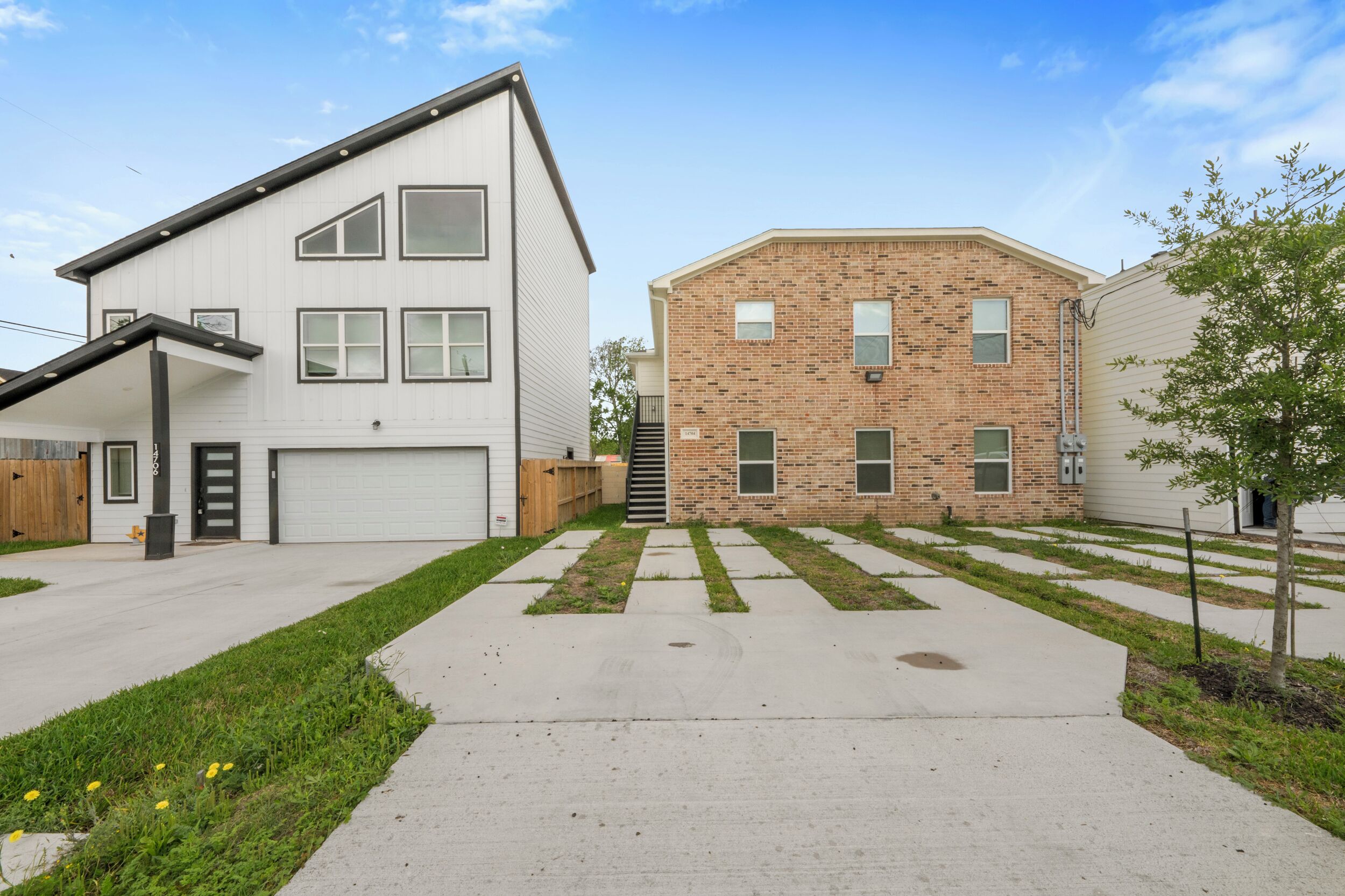 A residential area with two houses, one with a garage and the other with a brick facade.
