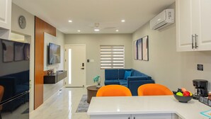 A modern kitchen with white cabinets, a dining area with a white table, and a blue sofa. - Blue Haven Suite at Black Pineapple Cottages (Cedar Grove)