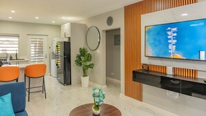 A modern living room with a flat-screen TV, a coffee table, and a sofa. - Blue Haven Suite at Black Pineapple Cottages (Cedar Grove)