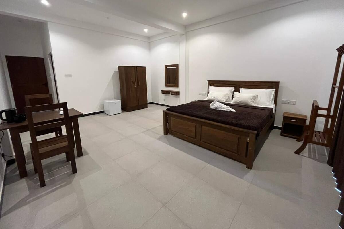 A bedroom with a large bed, a wooden chair, a small table, and a wardrobe.