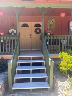 A wooden staircase leading to a door with a wreath and a welcome sign.