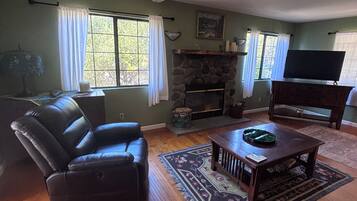 Una sala de estar con chimenea, televisor y sofá de cuero.