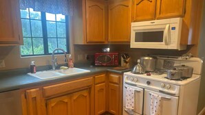 A kitchen with wooden cabinets, a microwave, a stove, and a sink.