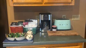 A kitchen with wooden cabinets, a coffee maker, a toaster, and a fruit bowl.