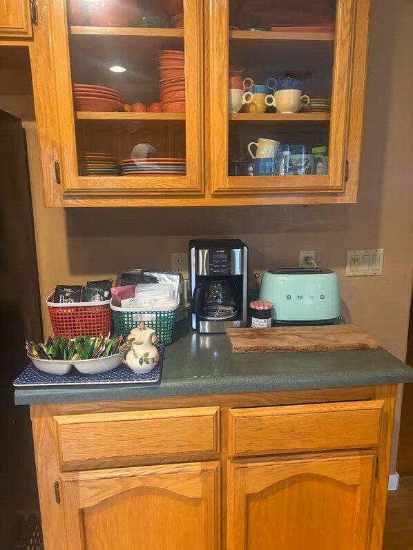 Una cocina con armarios de madera, cafetera, tostadora y frutero.
