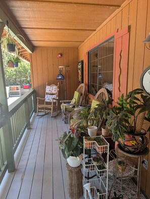 A wooden porch with a railing, chairs, and potted plants. - Rustic Canyon Retreat (Salinas)