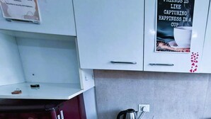 A kitchen with a microwave, kettle, and a tray of mugs. - Cozy 1-BHK entire apartment at good height Balcony (Gurugram)