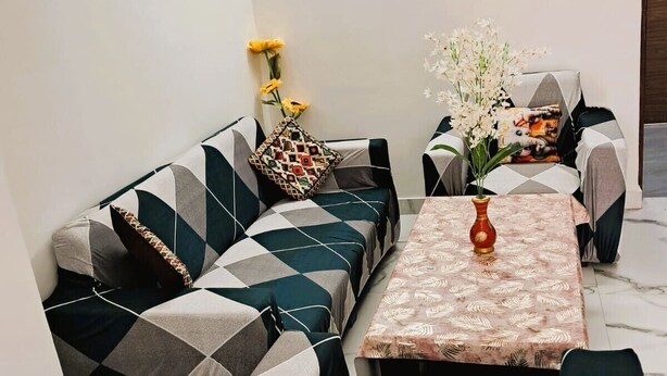 A modern living room with a sofa set, a coffee table, and a wall-mounted air conditioner. - Cozy 1-BHK entire apartment at good height Balcony (Gurugram)