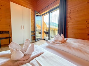 Une pièce de style cabane en bois, avec deux lits, un banc et une porte-fenêtre coulissante donnant sur un espace extérieur.