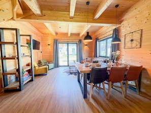 Un intérieur en bois comprenant un coin repas, un canapé et une bibliothèque.