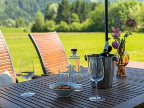 A table with a bottle of champagne, glasses, a bowl of nuts, and a vase of flowers. - Lovely holiday home on park near ski resort (Rattendorf)