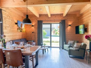 Un intérieur en bois comprenant un coin repas, un canapé et un téléviseur.