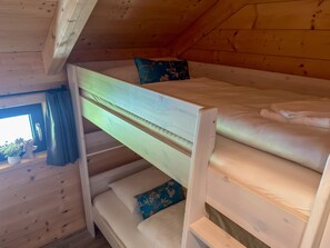 A bunk bed in a wooden cabin room with a window and a potted plant. - Lovely holiday home on park near ski resort (Rattendorf)