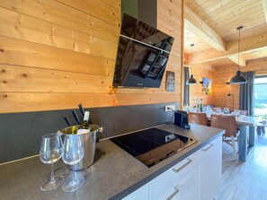 A modern kitchen with a built-in stove, wine glasses, and a Samsung microwave. - Lovely holiday home on park near ski resort (Rattendorf)