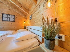 A wooden cabin room with two beds, a wall-mounted light fixture, and a potted plant. - Lovely holiday home on park near ski resort (Rattendorf)