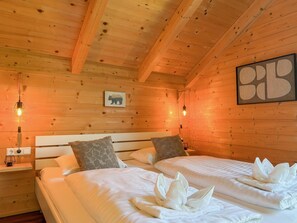 Un dormitorio de cabaña de madera con dos camas, un cuadro colgado en la pared y techo de madera.