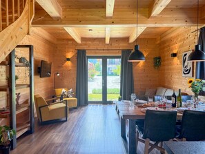 A wooden interior with a dining area, sofa, and staircase. - Lovely holiday home on park near ski resort (Rattendorf)
