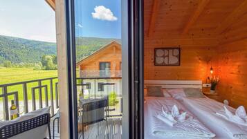 Eine Holzdiele mit einem Balkon, einem Bett mit ordentlich bezogenen Kissen und einem gerahmten Kunstwerk an der Wand.