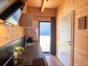 Une cuisine avec des murs en bois, un évier, une cuisinière et une fenêtre.