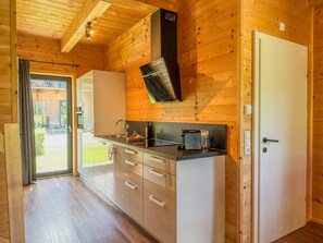 Un intérieur en bois avec un coin cuisine comprenant un évier, des placards et une machine à café.