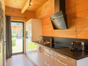 Eine moderne Küche mit Holzwänden, einem Edelstahlspülbecken und einer eingebauten Dunstabzugshaube.