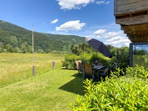 Une terrasse avec des meubles d’extérieur, une table et un parasol.