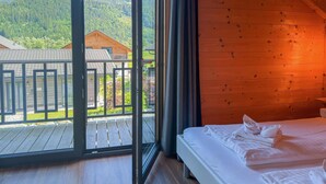 A room with a bed, a large window, and a view of a forested mountain. - Lovely holiday home on park near ski resort (Rattendorf)