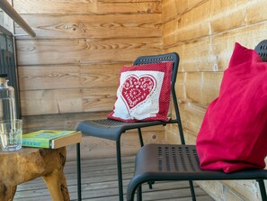 A wooden interior with a chair, a red pillow, a glass, and a book on a wooden table. - Lovely holiday home on park near ski resort (Rattendorf)