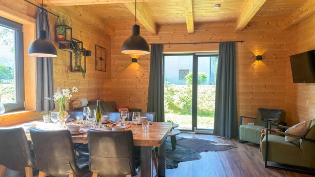 A wooden interior with a dining table, chairs, and a sofa. - Lovely holiday home on park near ski resort (Rattendorf)
