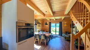 A wooden interior with a kitchen, dining area, and staircase. - Lovely holiday home on park near ski resort (Rattendorf)