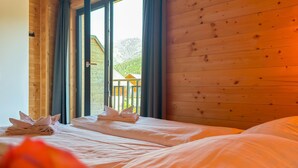 A room with two beds, wooden walls, and a view of a wooden structure outside. - Lovely holiday home on park near ski resort (Rattendorf)