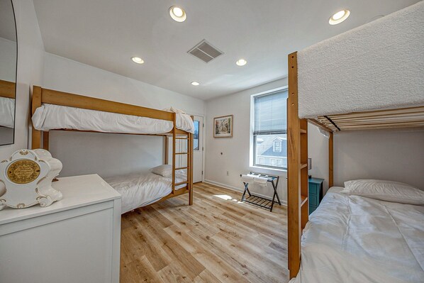 A room with bunk beds, a desk, a chair, and a window.