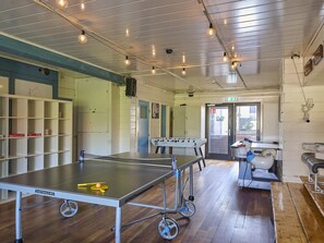A ping pong table with a net, a foosball table, and a billiards table in a room with wooden floors and white walls. - House in Kaag with rooftop terrace and spa bath. (Kaag)