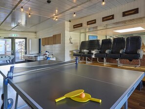 A ping pong table with a paddle and ball, a seating area with chairs, and a wall with framed items. - House in Kaag with rooftop terrace and spa bath. (Kaag)