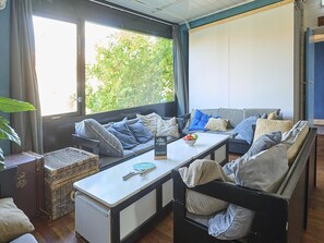 Ein gemütliches Wohnzimmer mit einer Couch, einem kleinen Tisch und Blick auf Grünfläche.