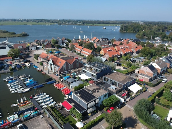 An aerial view of a marina with boats docked, surrounded by residential buildings with red roofs.