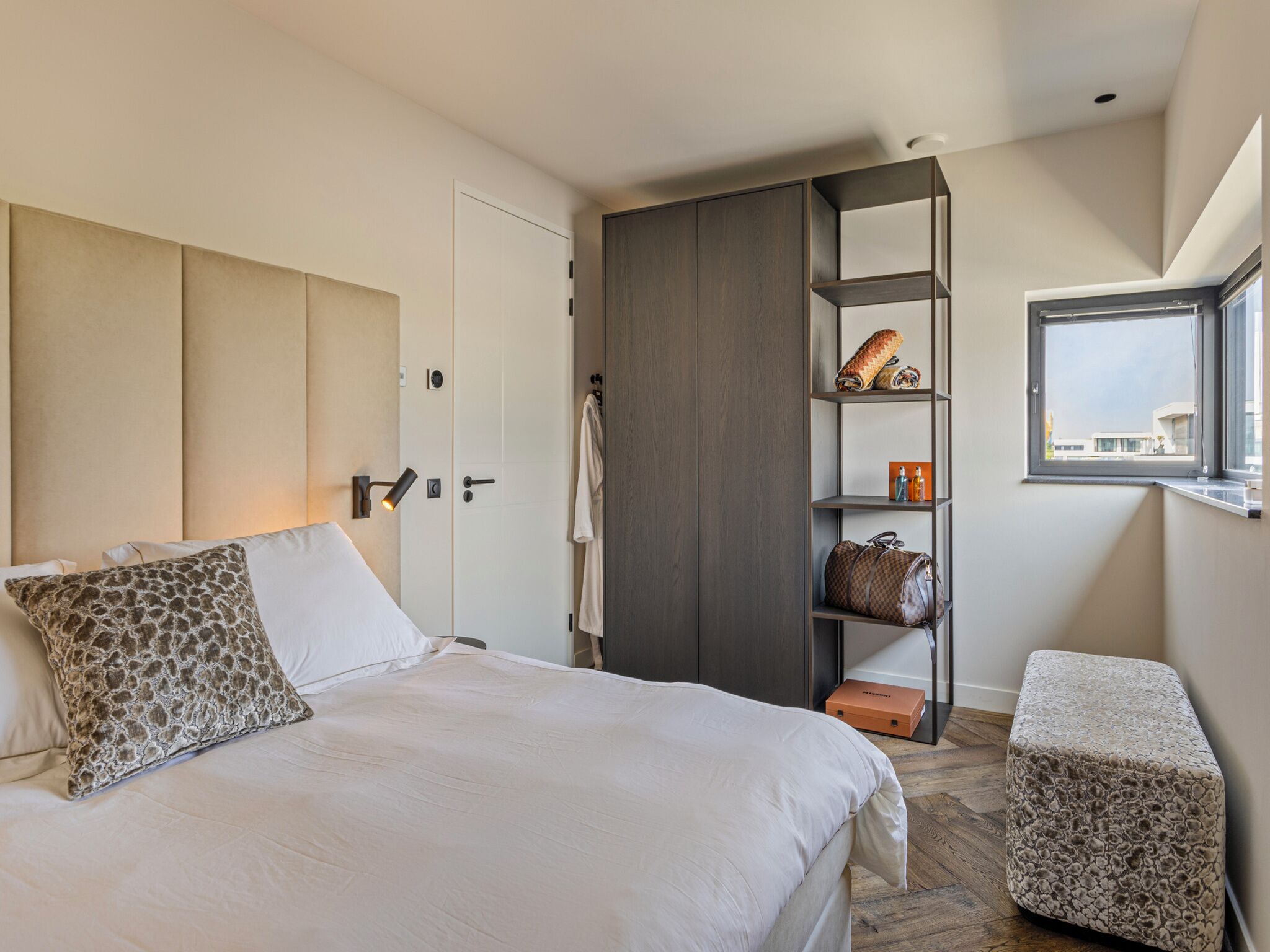 Une chambre à coucher avec un lit, une armoire, une petite table et une fenêtre.