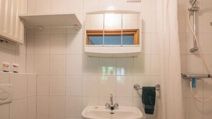 Een badkamer met een wastafel, een raam erboven en een douche aan de rechterkant.