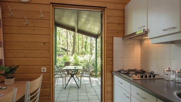 Een compacte keuken met een gasfornuis, witte kastjes en een zithoek met een tafel en stoelen.