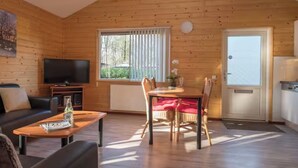 A cozy cabin with a TV, a dining table, and a sofa.