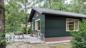 A small house with a porch, a bicycle, and outdoor furniture.