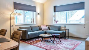 Ein modernes Wohnzimmer mit Sofa, Couchtisch und Essbereich mit Stühlen.