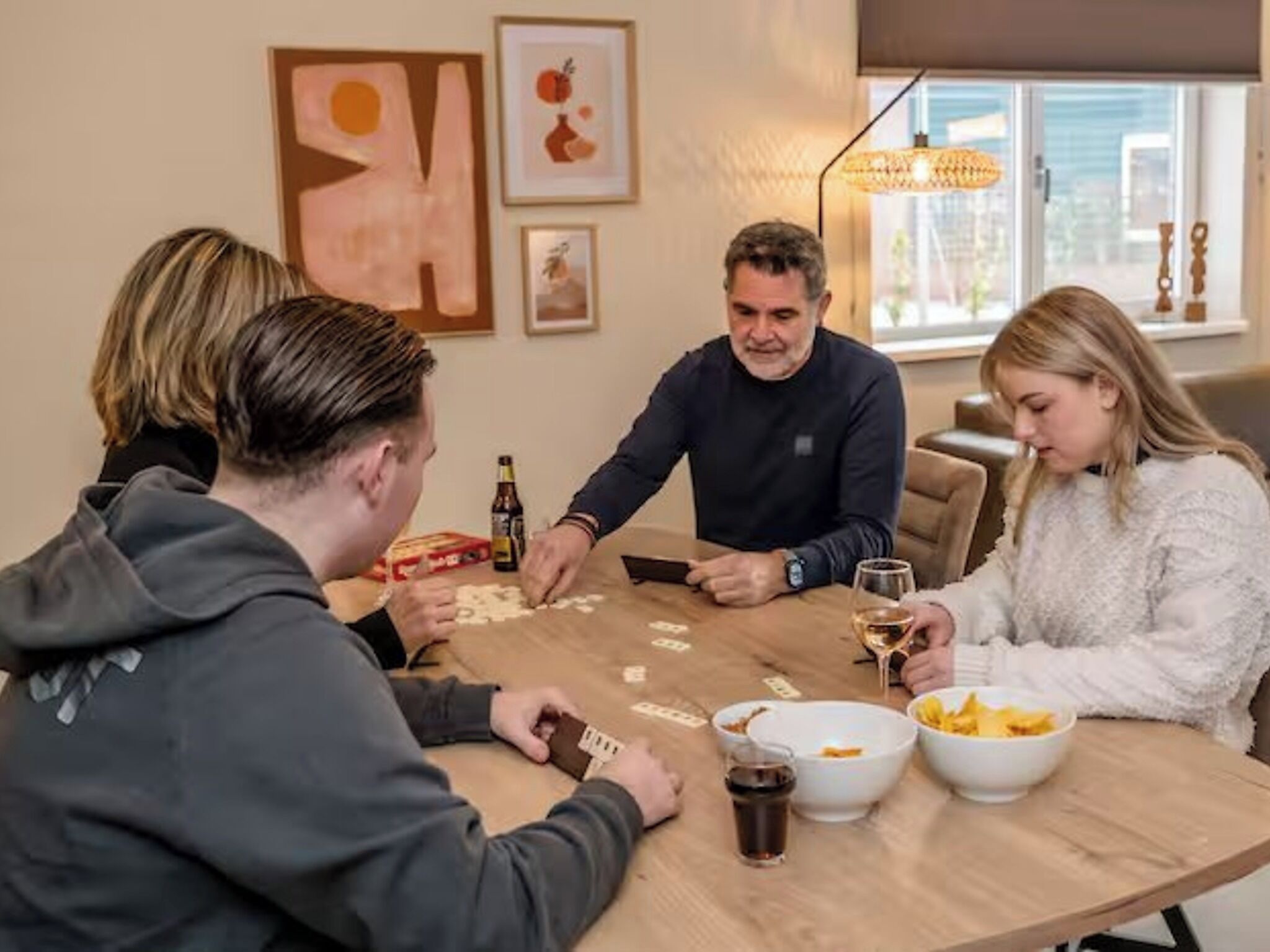 Un groupe de personnes jouant à un jeu de société autour d’une table ronde, avec des collations et des boissons.