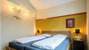 Ein Doppelbett mit Holzrahmen, zwei Nachttische mit Lampen sowie eine Wandleuchte.