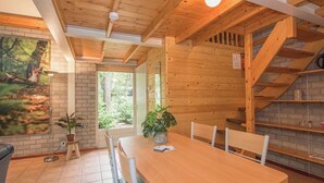 A wooden interior with a dining table, chairs, a potted plant, and a staircase. - Romantic holiday home with sleeping loft for 2 (Heesch)
