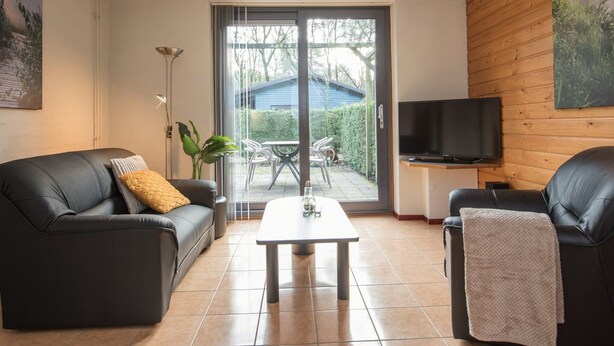Una sala de estar con sofá, mesa de centro, televisor y puerta corrediza de vidrio que da a un patio.