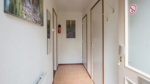 Un pasillo con paredes blancas, puertas de madera y suelo de baldosas.