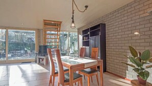 A spacious dining area with a large table and chairs, a television, and a brick wall.